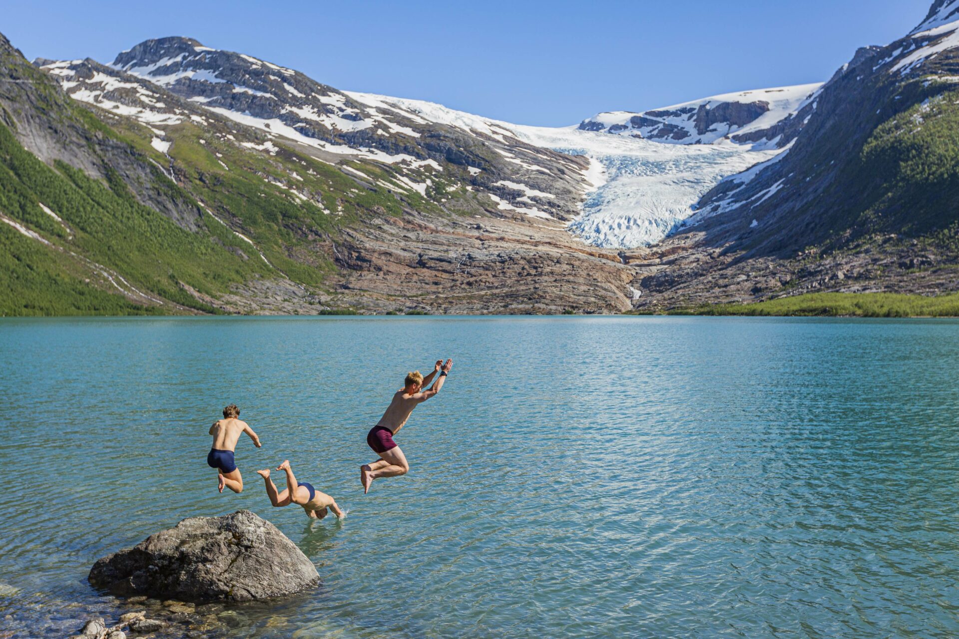 Gutter som hopper i vannet fremfor isbre